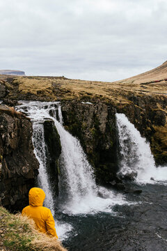 Traveler in yellow jacket views Icelandic waterfall