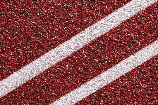 Red running track surface with white lane lines, textured rubber material close up, vibrant sports background for athletic competition and training environment