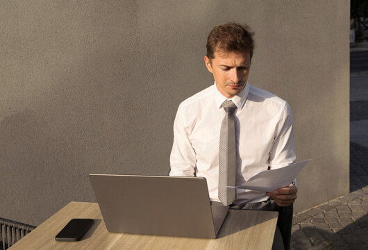 Young businessman review document at outdoor laptop workspace