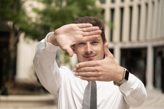 Young businessman framing view with hands outdoors