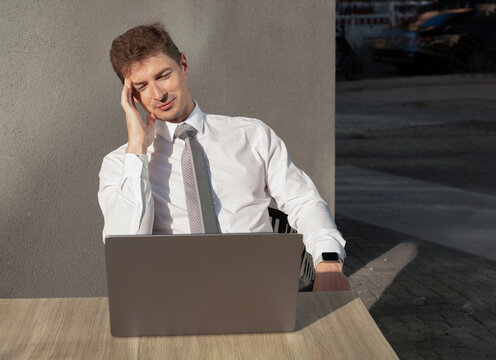 Stressed young businessman work on laptop outdoors