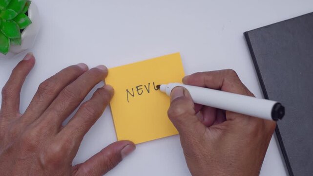 A man writing never give up on orange sticky note