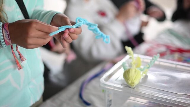Child's hands twisting pipe cleaner for diy art project during a creative workshop close up of handmade crafting