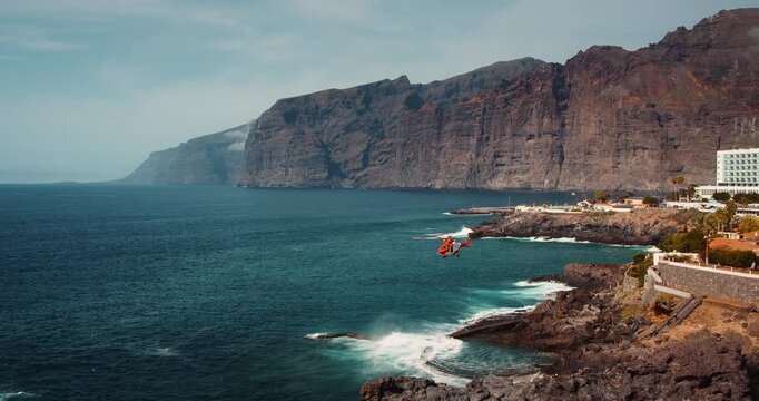 TENERIFE, CANARY ISLANDS, SPAIN, 2023 April: Guard helicopter search and rescue mission in open ocean. Aerial aviation provides first aid to the injured on rocky shore.
