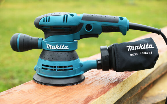 Makita random orbit sander on wooden board outdoors.