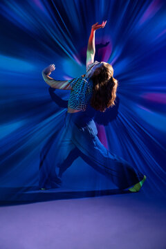 Young woman dance in vibrant blue light studio