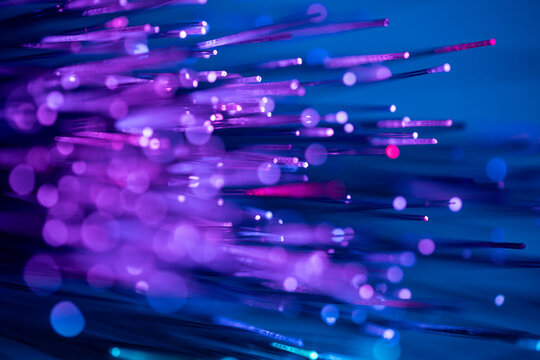 Glowing fiber optic strands on blue technology background