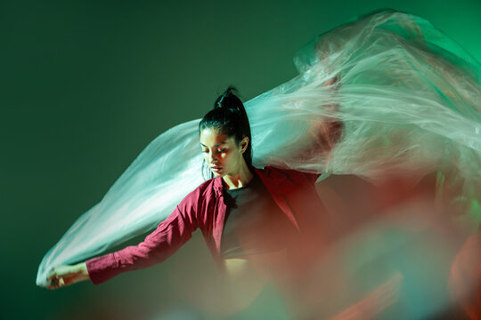 Latin woman dancer with flowing fabric in colorful light