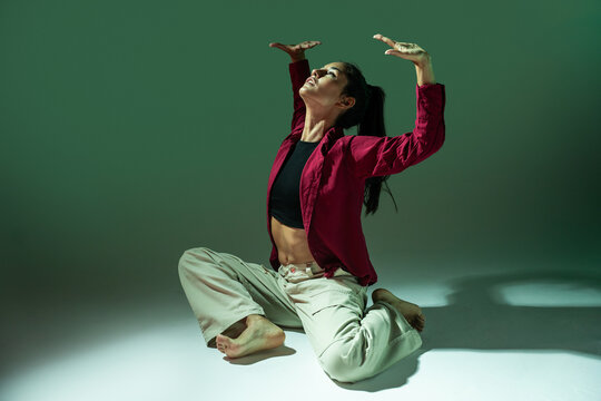 Latin woman dancer posing barefoot in dramatic studio light