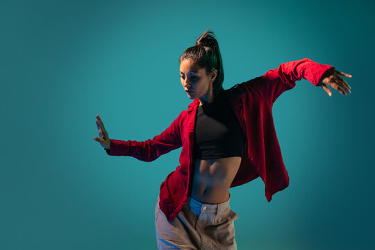 Latin woman dancer pose in red jacket against teal background
