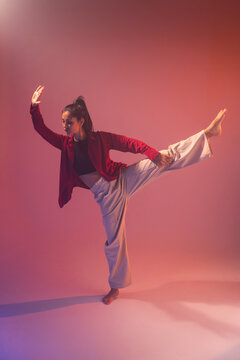 Latin woman dancer perform high kick in colored studio