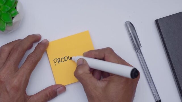 A man writing porductivity on orange sticky note