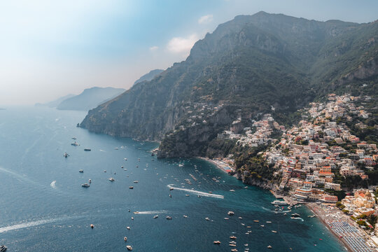 Aerial view of the colorful buildings of Positano nestled on the cliffs of the Amalfi Coast with numerous boats in the turquoise sea, Positano, Campania, Italy.