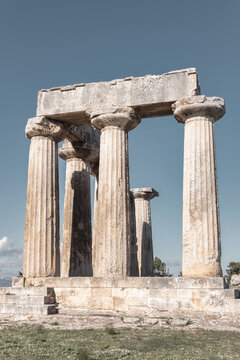 Ancient Doric columns of Apollo temple in Corinth, Greece with warm sunlight and clear sky