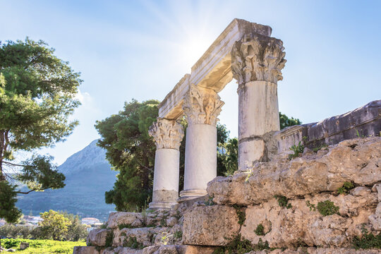 Corinthian columns and stone ruins in the archaeological park of ancient Corinth, Greece at sunny day
