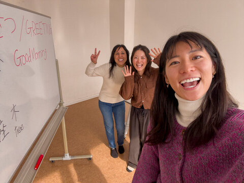 Japanese women smile beside whiteboard in language class