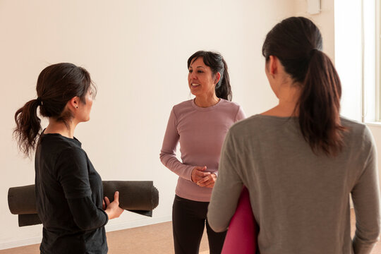 Japanese women converse before yoga class in bright studio