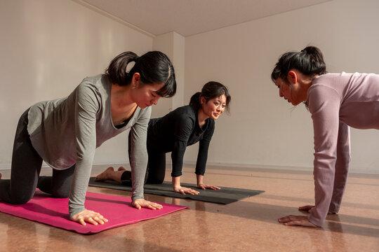 Japanese women practice yoga on mat in fitness class