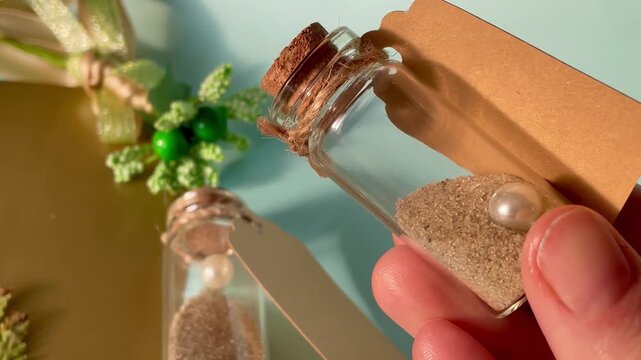 Female hand holding small glass bottle with sand and pearl