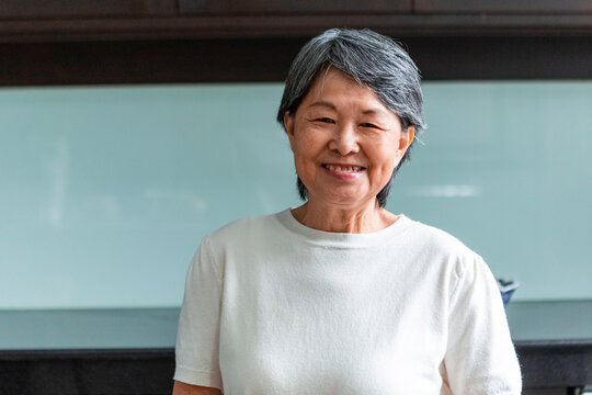 Smiling senior Asian woman in white shirt at home