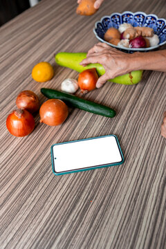Smartphone beside fresh vegetable on kitchen table