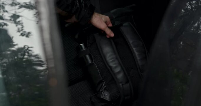 Man taking black travel backpack from car back seat with audio included