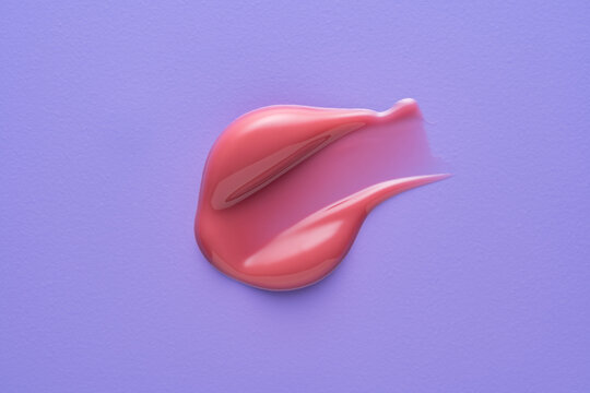 Pink lip gloss smear texture on colorful purple background