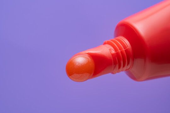 Red lip gloss texture on colorful purple background