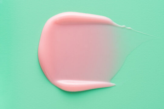 Pink lip gloss smear on mint green background
