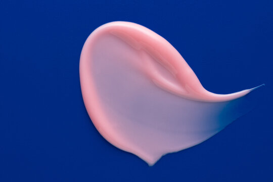Pink lip gloss smear texture on blue background