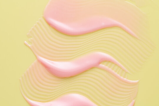 Pink lip gloss smear with wavy texture on yellow background