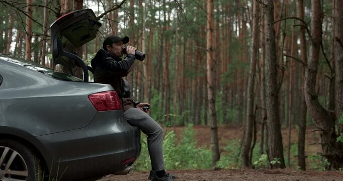 Male traveler resting in vehicle boot and drinking hot tea during road trip, audio included