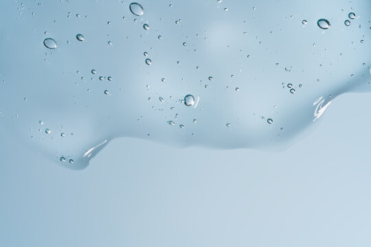 Transparent cosmetic gel texture with water droplet on blue