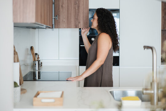 Woman open cabinet in modern apartment kitchen