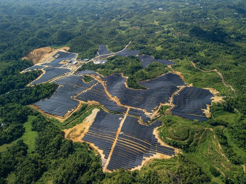 Aerial view of Sikatuna Solar Power Plant featuring rows of solar panels installed on hilly terrain surrounded by lush green tropical vegetation in Sikatuna, Central Visayas, Philippines.