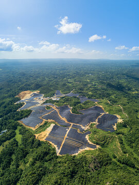 Aerial view of Sikatuna Solar Power Plant featuring rows of solar panels integrated into the hilly, forested landscape under a clear blue sky in Sikatuna, Central Visayas, Philippines.