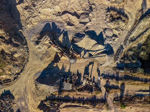 Aerial view of a quarry operation with heavy machinery, piles of gravel, and dirt roads in Calcium, Queensland, Australia.