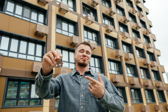 Homeowner hold house key outside modern apartment building