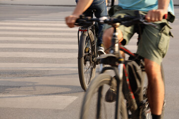 Fototapeta premium 2 Two cyclists are riding towards each other, breaking the rules, on an asphalt road at a pedestrian crossing Unrecognizable young adult male persons