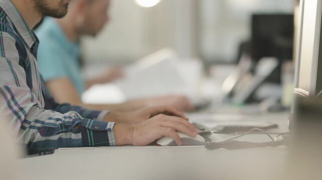 Man typing on keyboard at desk in bright office