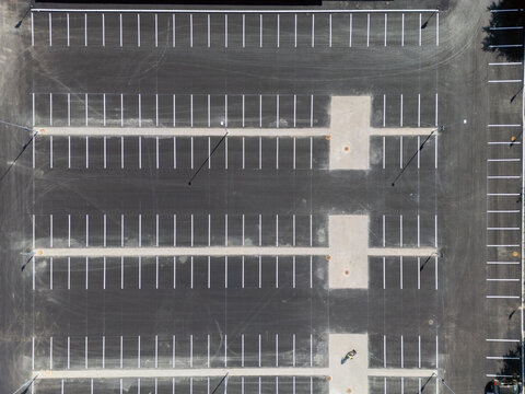 Aerial view of an empty asphalt parking lot with white painted parking spaces and light poles in Oulu, North Ostrobothnia, Finland.