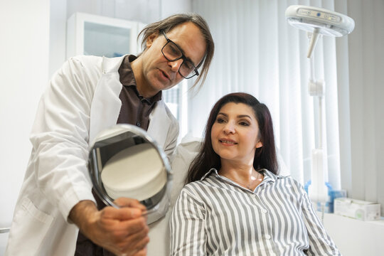 Doctor shows patient mirror during beauty clinic consultation