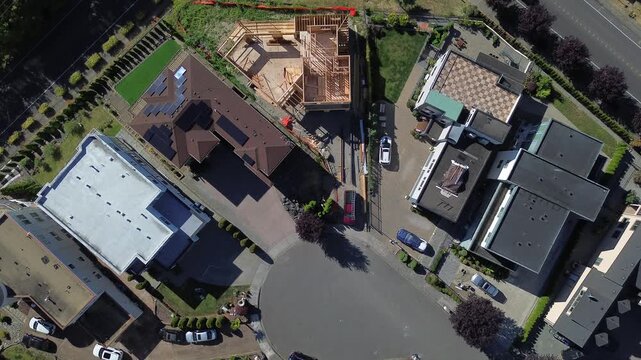 Central cul de sac defines Redondo, Seattle suburb enclave of Des Moines near South 272nd Street. Direct top down view shows active wood framing progress, uncovered floor decks, unfinished roof