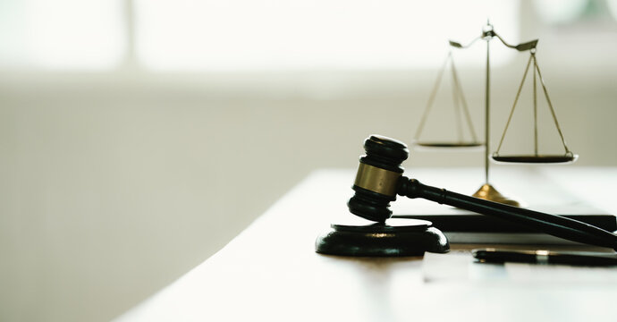Judge's gavel resting on a sound block with balanced scales of justice in the background, symbolizing law, justice, legal authority, and courtroom decisions.