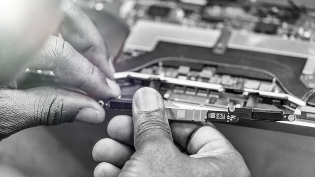 Back view of technician repairing laptop in electronics workshop with tools