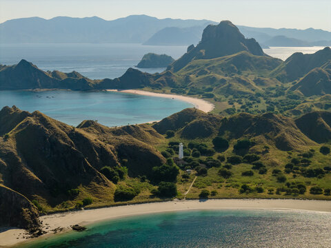 Aerial view of the rugged landscape and turquoise bay of Padar Island with its sandy beaches and lush hills in Komodo, East Nusa Tenggara, Indonesia.
