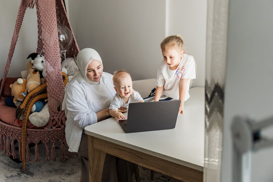 Mother and children use laptop together at home