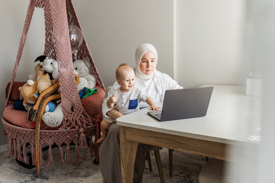 Mother and baby use laptop at home