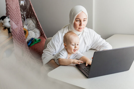 Muslim mother and baby use laptop at home together