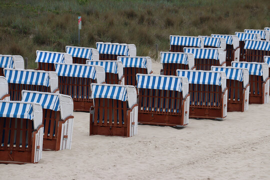 Rows of Strandkorb, a traditional German hooded windbreak seating furniture with blue-and-white-striped sun awning at the beach (G&ouml;hren, Baltic Sea, Germany)